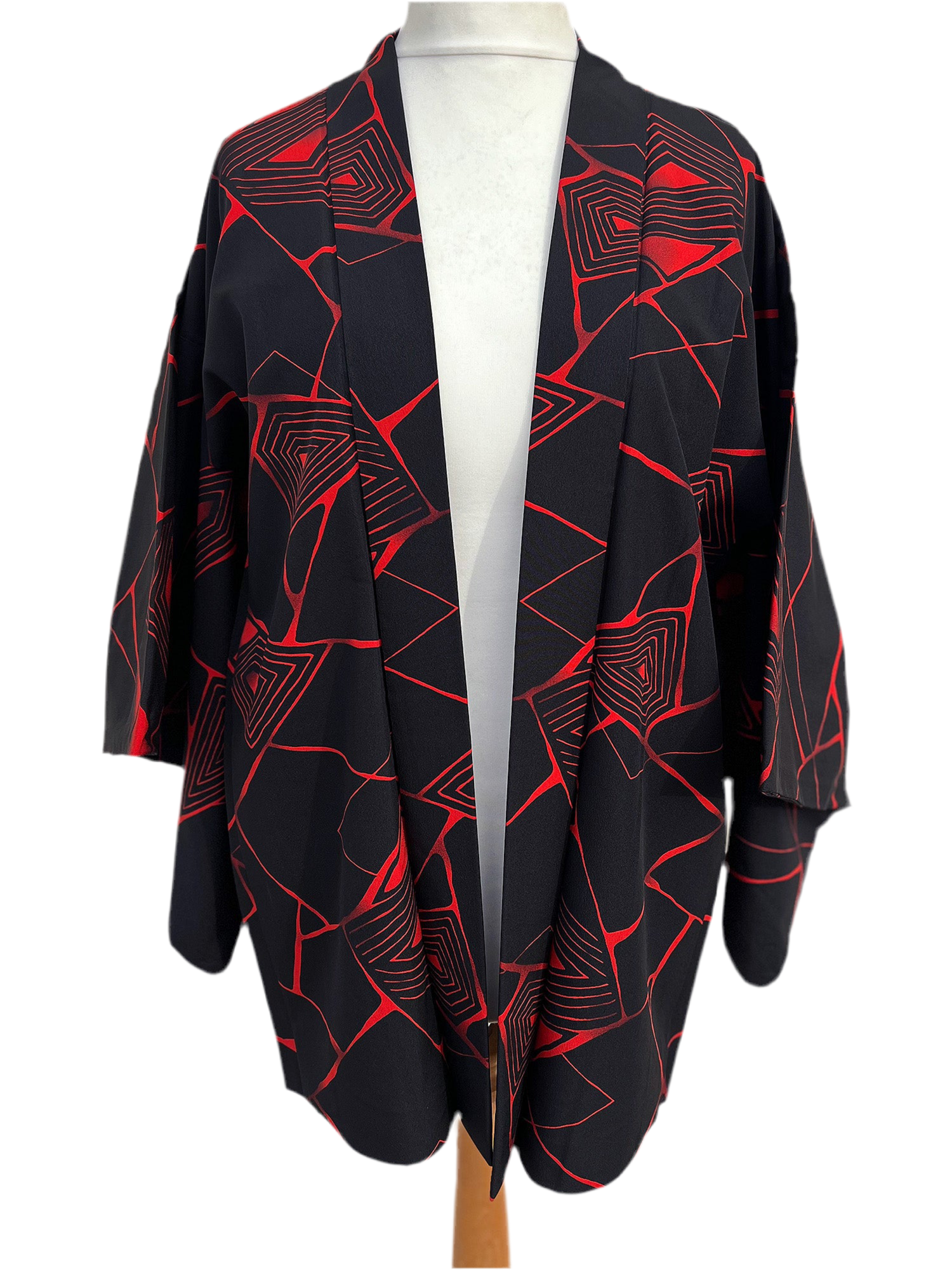 Black kimono-style haori jacket featuring an abstract red geometric pattern, upcycled from vintage Japanese fabric, lightweight and open-front design, displayed on a hanger