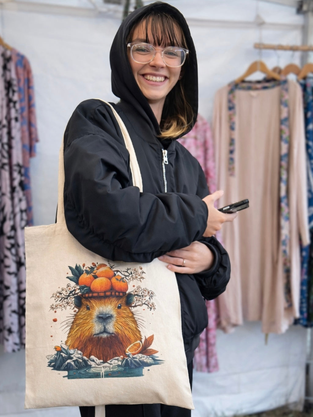 Woman carrying a natural canvas tote bag with Japanese capybara onsen illustration featuring citrus and cherry blossoms.